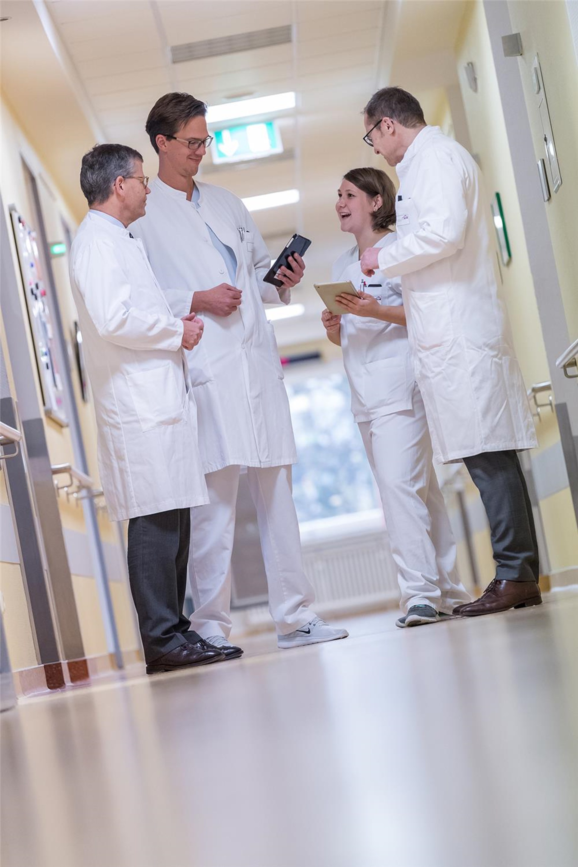 Vier Krankenhaus-Mitarbeitende auf dem Krankenhausflur